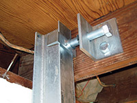 Securing the i-beam system to the top of the floor joist in a foundation wall repair in Terrebonne.