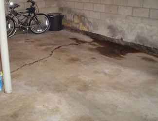 Inondation provenant du plancher. Les fissures de plancher exposent le plancher du sous-sol à l'eau sous la dalle.